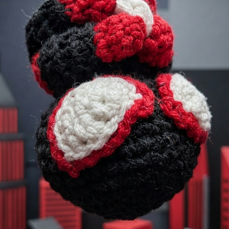 Crocheted boxing glove ornament hanging against a dark background