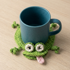 Blue mug on a green frog-shaped coaster on a wooden surface